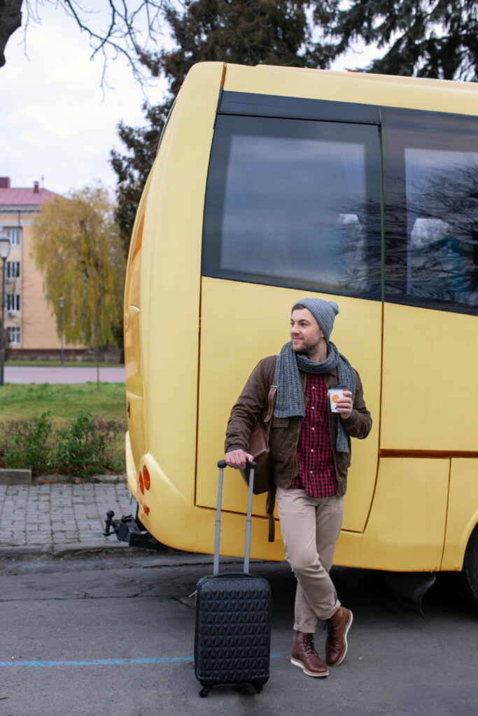 Traveller with a suitcase standing next to a coach